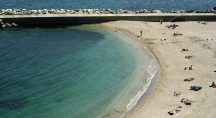Relaxing beach day in Ancona, Italy with clear waters and sunbathers enjoying summer.