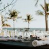 Elegant seaside outdoor dining setup with glassware and ocean view, ideal for luxury events.
