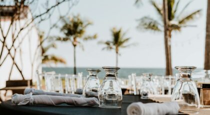 Elegant seaside outdoor dining setup with glassware and ocean view, ideal for luxury events.