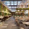 Elegant restaurant interior featuring chandeliers, greenery, and stylish dining furnishings.