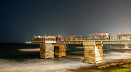 Stunning night view of the Galle Face pier in Colombo with tourists enjoying the sea breeze.