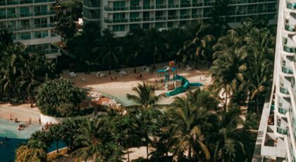 Aerial view of a luxury resort with swimming pool, palm trees, and leisure facilities, perfect for vacation and relaxation.