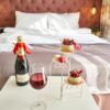 Elegant bedroom setting with champagne, wine glass, and desserts, creating a cozy ambiance.