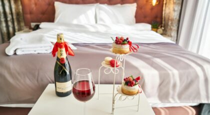 Elegant bedroom setting with champagne, wine glass, and desserts, creating a cozy ambiance.