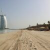 A stunning view of Burj Al Arab against the clear sky on a serene beach in Dubai, UAE.