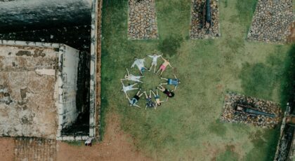 Drone shot of people forming a circle on grass at historic fort in Sri Lanka.