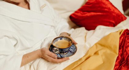 Relaxing morning in bed with a cup of coffee, wearing a bathrobe.