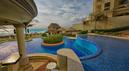 Relaxing poolside at a luxury resort in Mexico with scenic ocean views and palm trees.