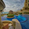 Relaxing poolside at a luxury resort in Mexico with scenic ocean views and palm trees.