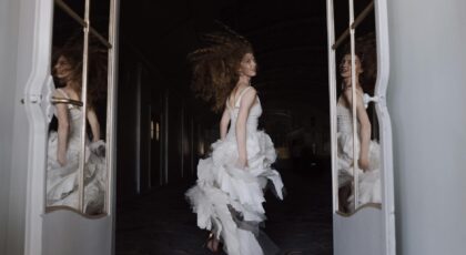 A bride in motion captures elegance and reflection in a grand hallway.