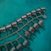 Stunning aerial shot of overwater bungalows in a tropical resort setting against turquoise sea waters.