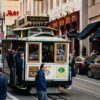 Iconic San Francisco cable car with passengers on a vibrant urban street, showcasing transportation and city life.