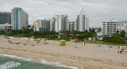Aerial view of beachfront cityscape with tall buildings and sandy shore.