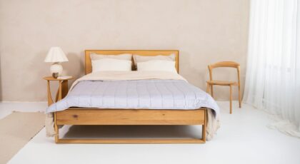 A serene minimalist bedroom with wooden bed frame, cotton bedding, and cozy decor.
