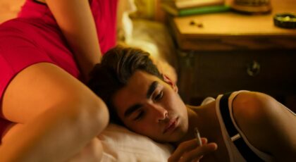 A couple relaxing in a cozy bedroom setting with warm lighting and intimate atmosphere.