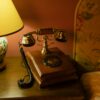 Classic hotel room decor featuring an antique telephone and floral lamp.