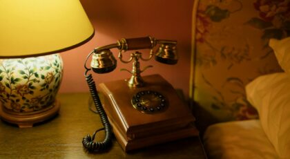 Classic hotel room decor featuring an antique telephone and floral lamp.