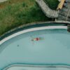 Aerial shot of a man floating peacefully in a resort pool surrounded by lush greenery, Sri Lanka.