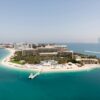 Stunning aerial shot of a luxury hotel on Dubai's Palm Jumeirah island, surrounded by turquoise waters.