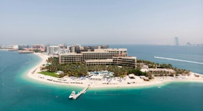 Stunning aerial shot of a luxury hotel on Dubai's Palm Jumeirah island, surrounded by turquoise waters.