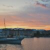 A stunning view of a city skyline with a boat at sunset, reflecting in calm waters.