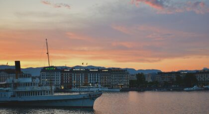 A stunning view of a city skyline with a boat at sunset, reflecting in calm waters.