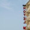 A modern hotel building with distinct balconies and a red sign against a clear blue sky.