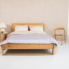 A serene minimalist bedroom with wooden bed frame, cotton bedding, and cozy decor.