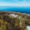 Scenic aerial view of a lakeside town with lush greenery and a grand hotel by the shore.