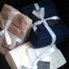 Three bundled sets of bath towels tied with ribbons, showcasing luxury and style.