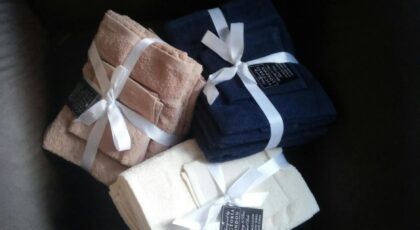 Three bundled sets of bath towels tied with ribbons, showcasing luxury and style.