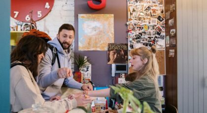 Guests checking in at a hostel reception with a warm interaction between a couple and staff.